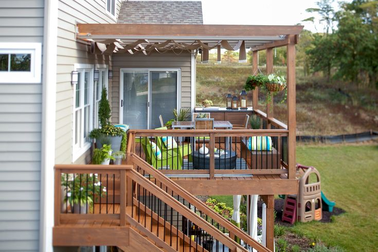 an outdoor deck with patio furniture and potted plants on the top floor, next to a house