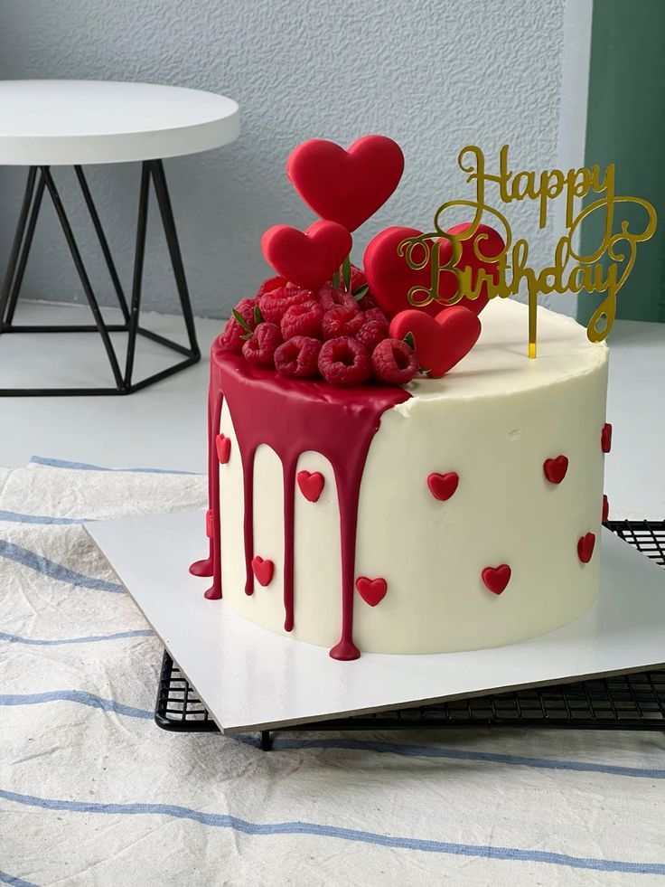 a birthday cake decorated with hearts and raspberries