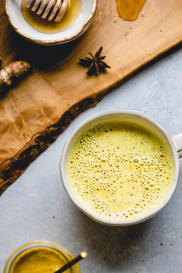 a cup of green tea next to some honey and spoons