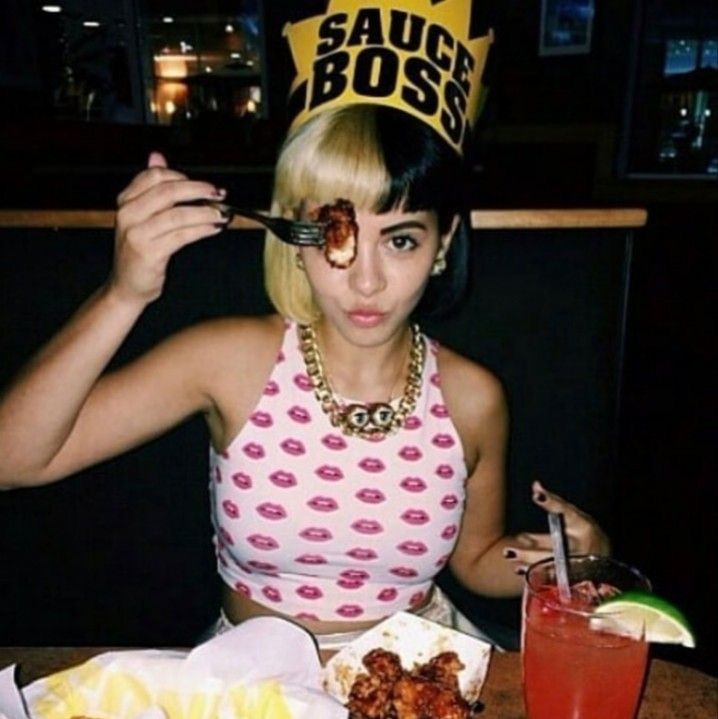 a woman sitting at a table with food in front of her and a crown on top of her head