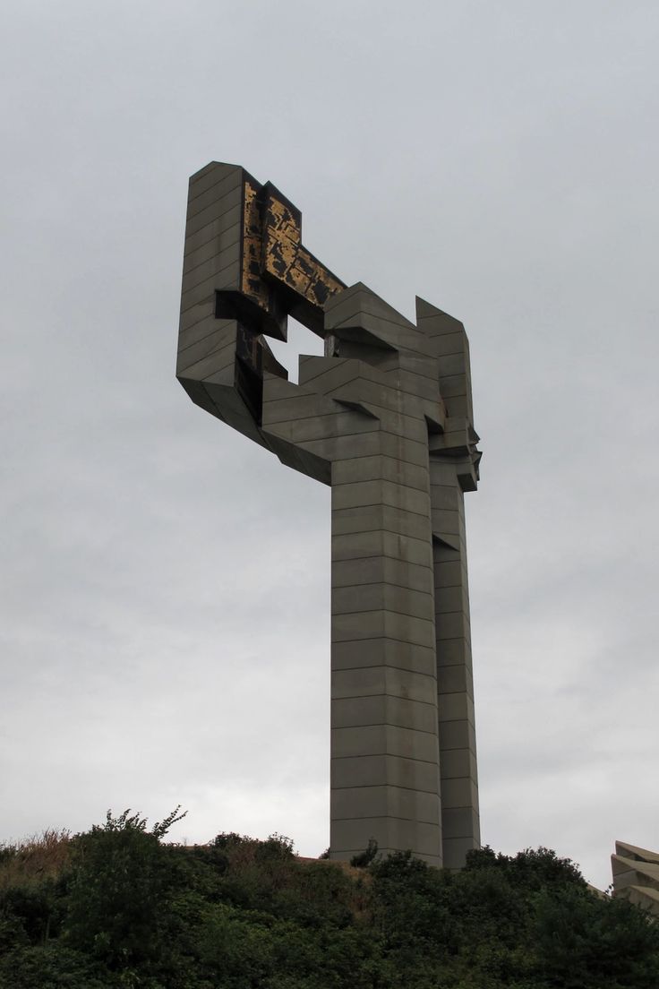 a very tall structure with a clock on it's side in the middle of a hill