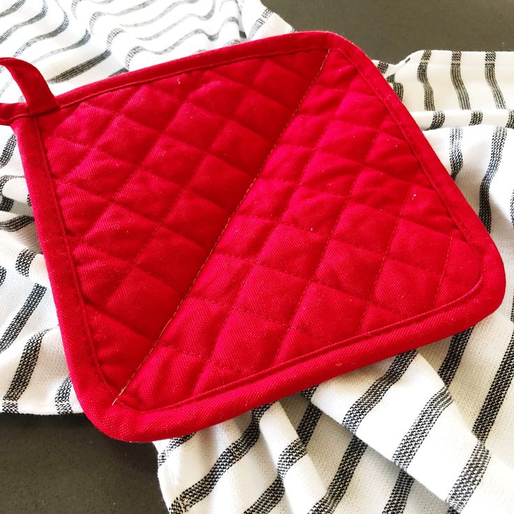 a red oven mitt sitting on top of a black and white towel