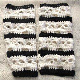 two black and white crocheted gloves on top of a lace tablecloth covered surface