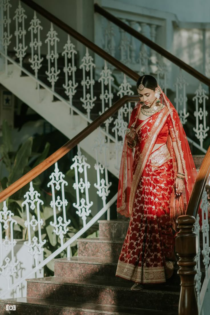 a woman in a red and gold sari walking down stairs