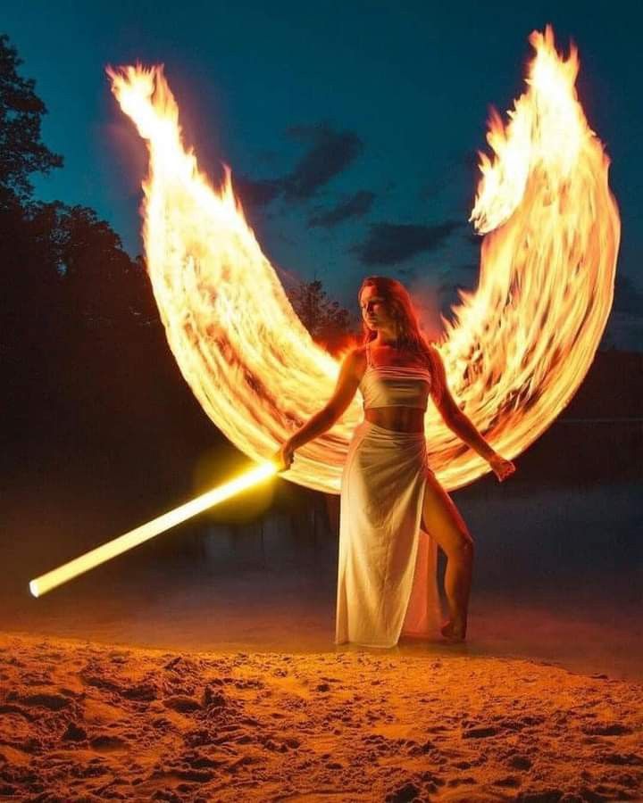 a woman is holding two fire wands on the beach