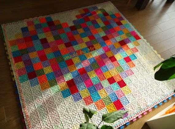 a multicolored blanket on the floor next to a potted plant