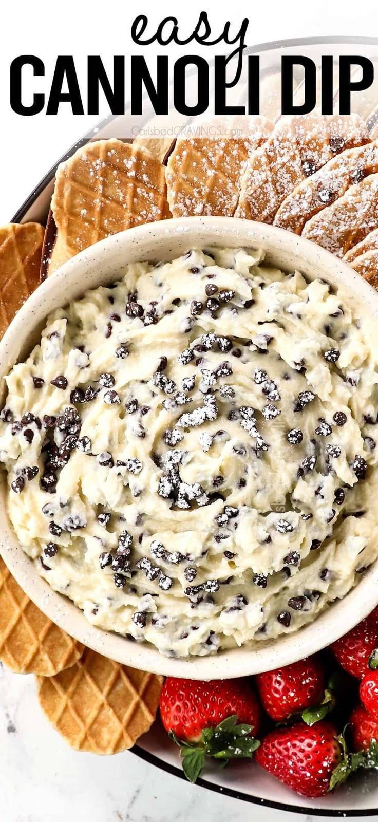 a bowl filled with cream cheese dip surrounded by crackers and strawberries on a plate