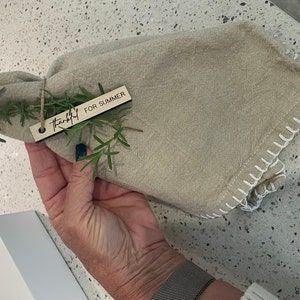 a person holding a small plant in their left hand and a tag that says for summer on it