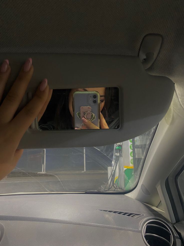 a woman taking a selfie with her cell phone in the back seat of a car