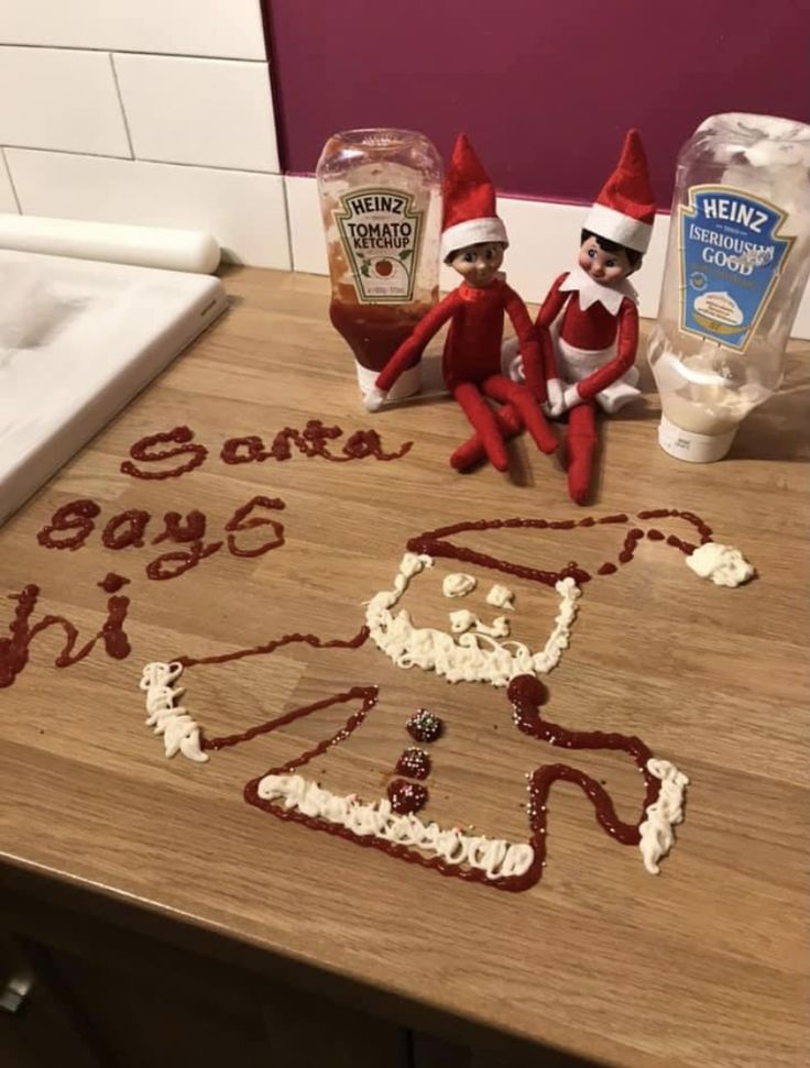 two elfs sitting on top of a wooden table next to doughnut holes and frosting