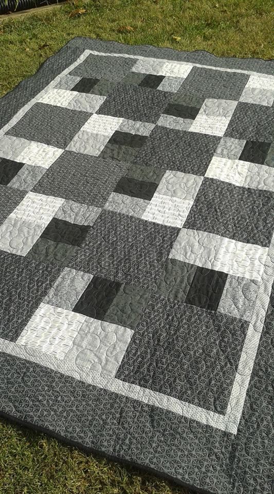 a black and white quilt is laying on the grass