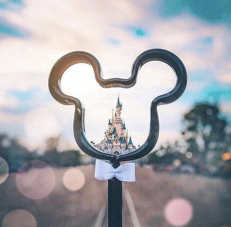 a close up of a mickey mouse head on top of a pole with a sky background