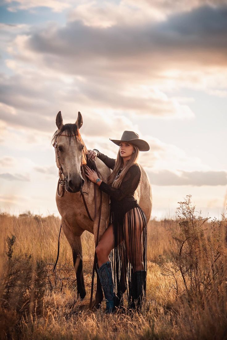 a woman in cowboy attire standing next to a horse