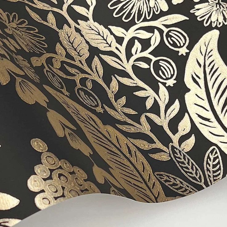 an artistic black and gold wallpaper with white flowers, leaves and scrolls on it