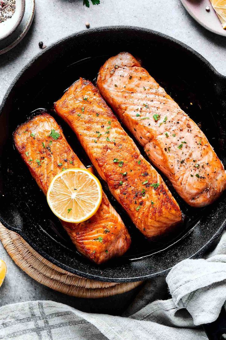 two salmons in a skillet with lemon slices