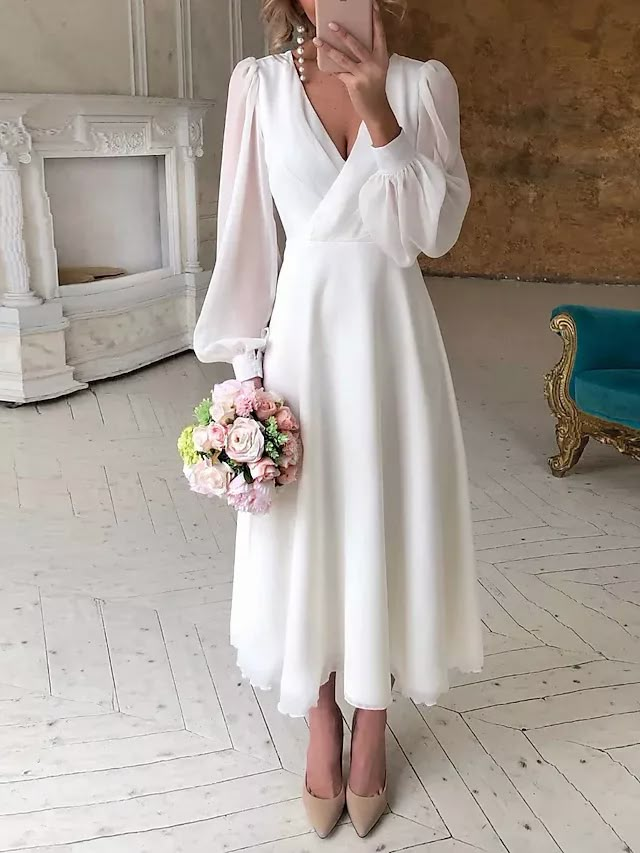 a woman in a white dress taking a selfie with her cell phone and holding a bouquet of flowers