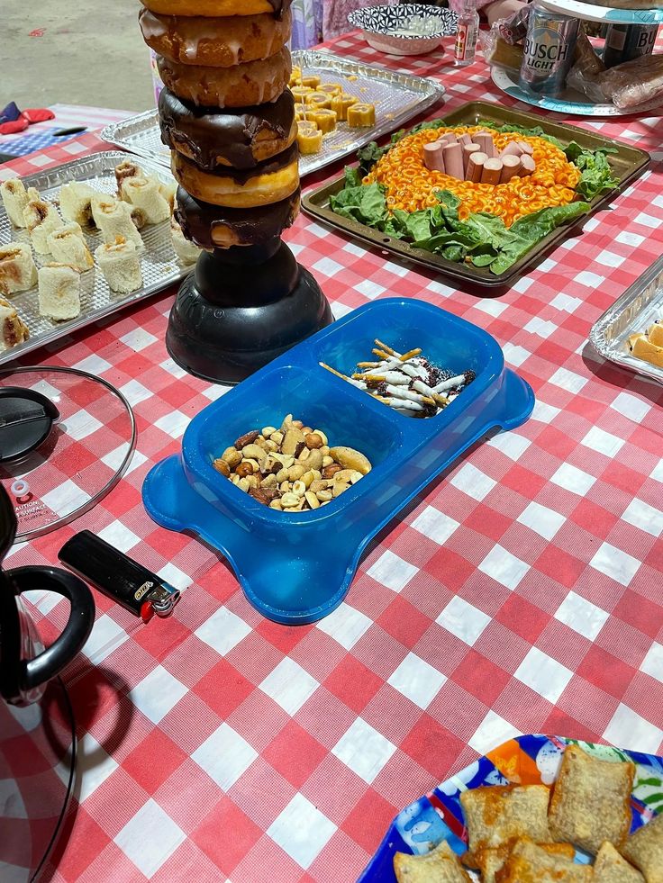 a table topped with lots of food on top of a red and white checkered table cloth