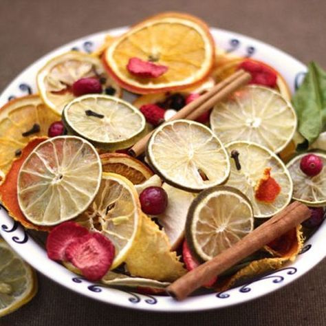 a white plate topped with sliced oranges and other fruits next to cinnamon sticks on top of a table