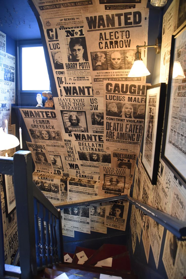 a room with many newspapers on the wall and stairs leading up to an open window