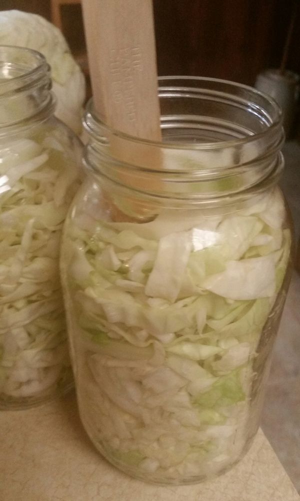 two mason jars filled with sliced onions and a wooden spoon