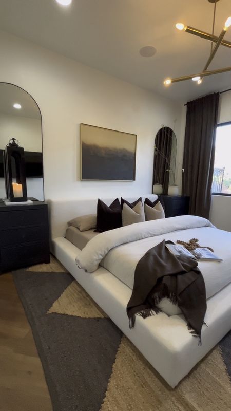 a large white bed sitting in a bedroom next to a window