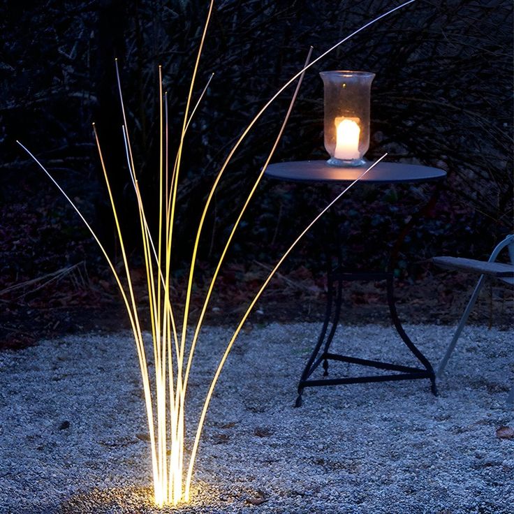 a lit candle sitting on top of a table in the middle of a field at night