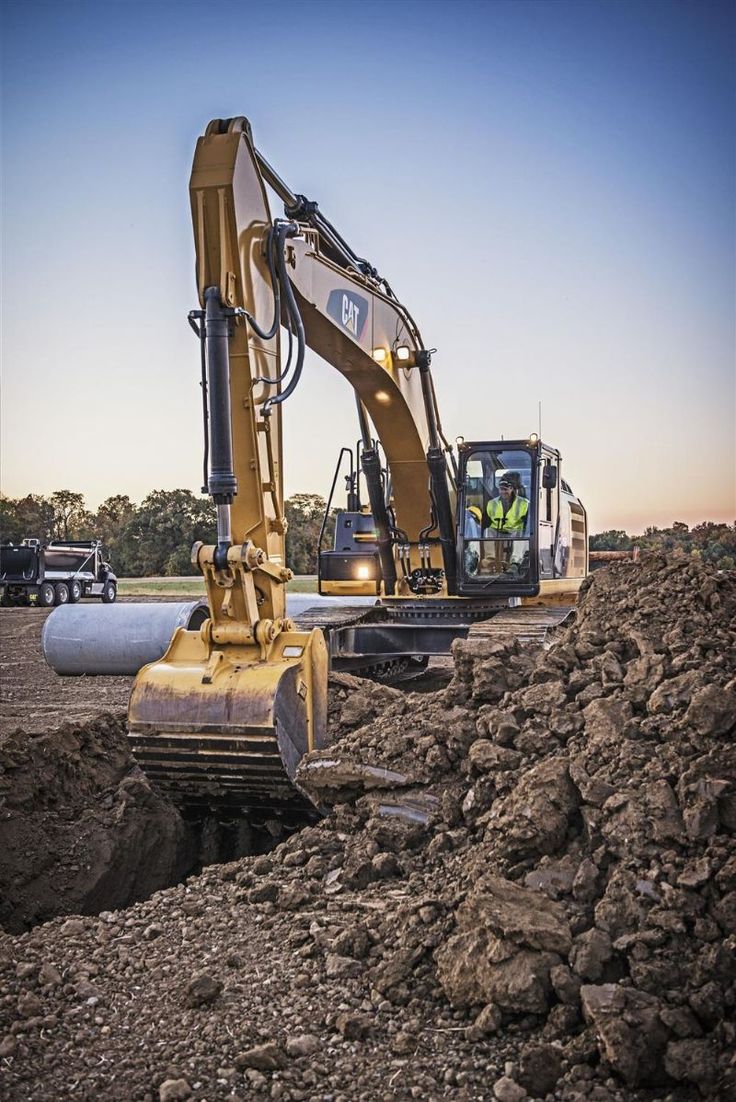 two large machines are digging through the dirt