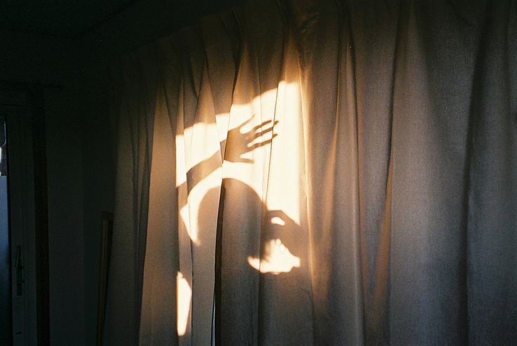 the shadow of a person's hand on curtains