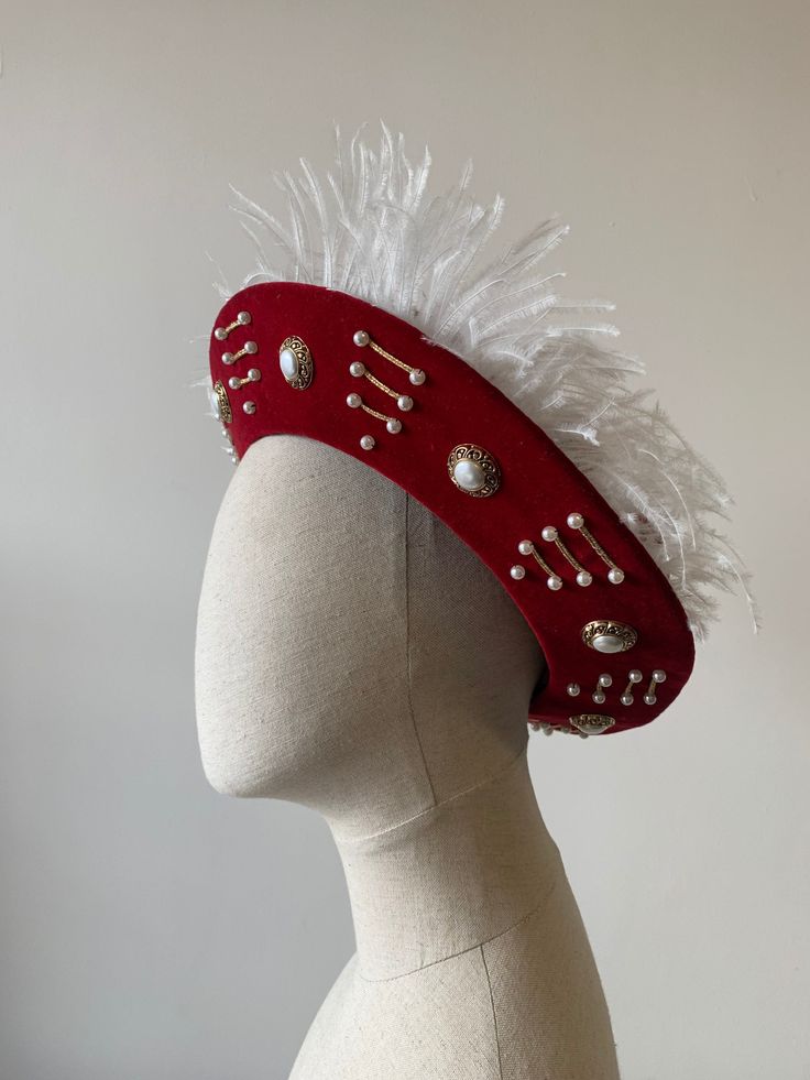 Men's red velveteen Tudor/Henrician bonnet, made to order. This hat features a sturdy buckram brim and comes with the trimming similar to the one seen in the photograph. The hat is made from a lovely rich red cotton velveteen, and lined with cotton. Trim options include pearls and brooches, plus a choice of white or coloured feathers, echoing the hats worn by Henry VIII in portraits from the period. Each hat is custom made to your specified head size. I don't keep ready-made stock of these, but Red Brimmed Costume Hat For Festival, Red Brimmed Costume Hats And Headpieces For Festivals, Red Brimmed Festival Costume Hat, Red Brimmed Festival Costume Hats And Headpieces, Red Costume Hat, Red Curved Brim Costume Hat For Festivals, Red Brimmed Hat For Costume, Red Costume Hat With Curved Brim For Festival, Vintage Red Hat For Costume Party