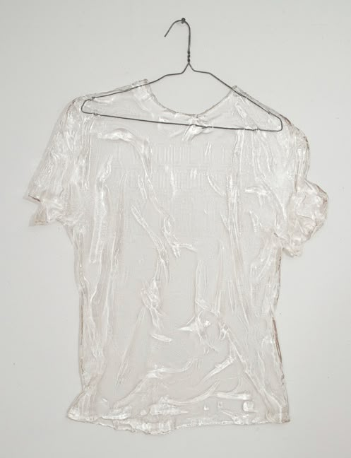 a white t - shirt hanging on a hanger with no clothes in front of it