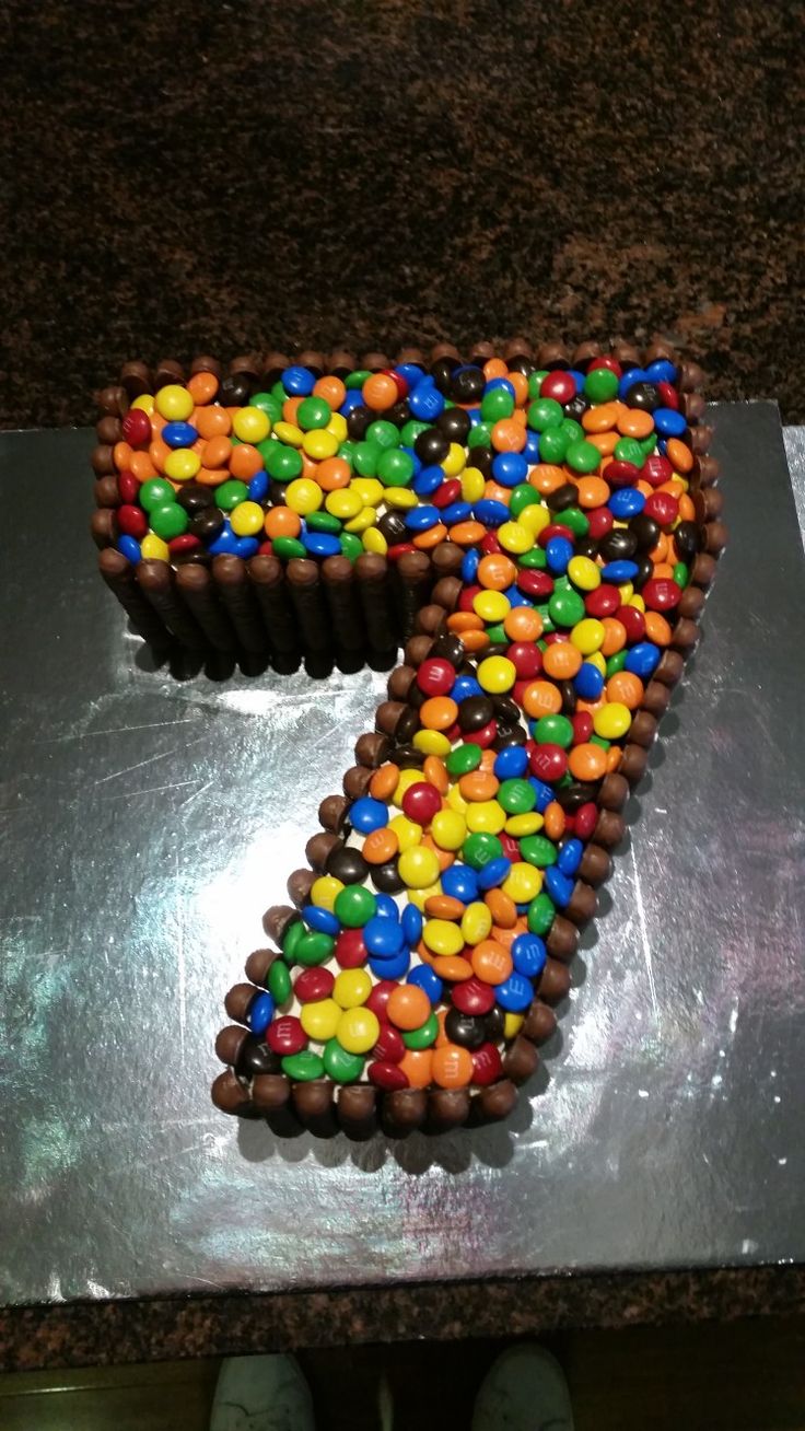 a cake shaped like the number seven with chocolate and candy candies on it's side