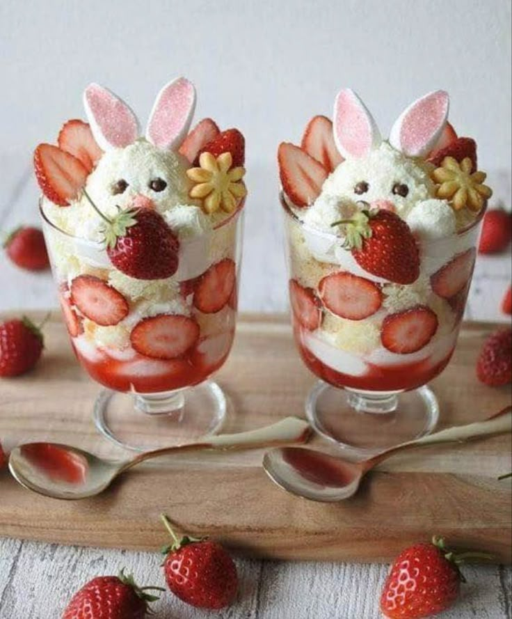 two glasses filled with strawberries and topped with whipped cream in the shape of rabbits