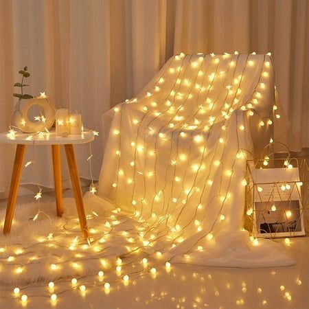 a white chair covered in fairy lights next to a small table