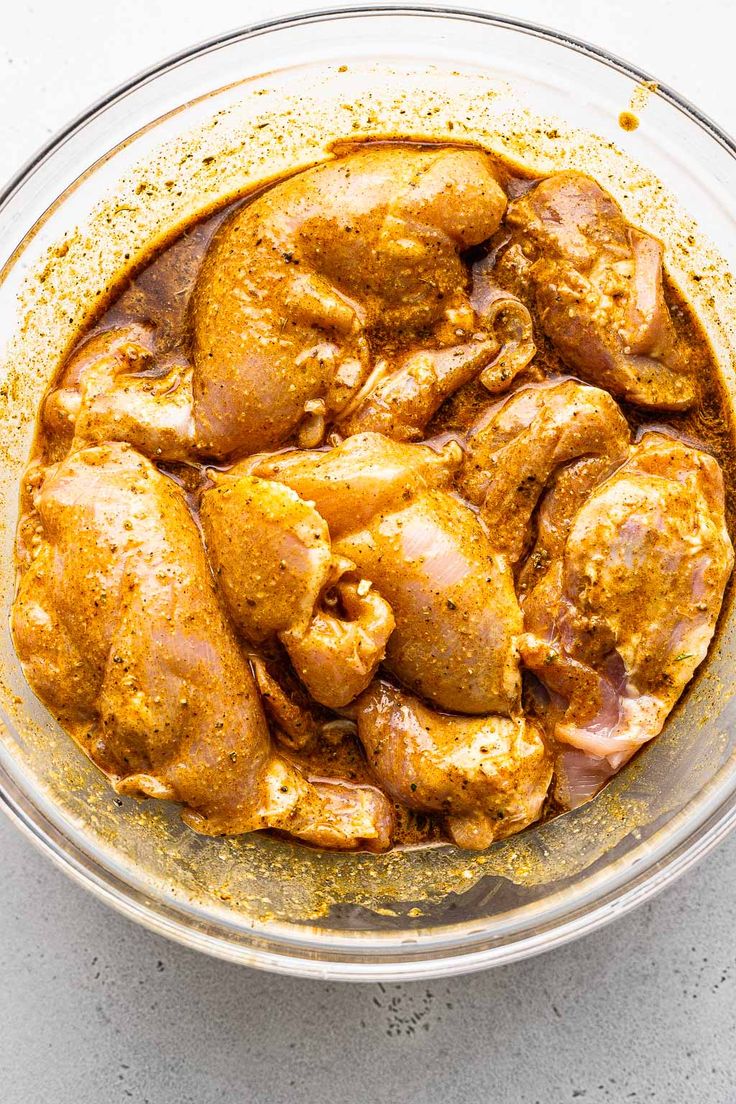 chicken curry in a glass bowl on a white counter top, ready to be cooked