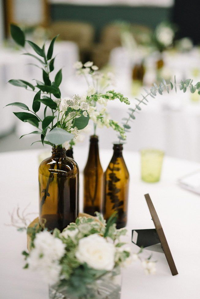 three brown vases with white flowers and greenery in them sitting on a table