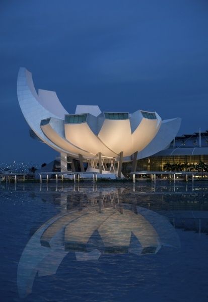 the lotus sculpture is lit up at night in front of a large body of water