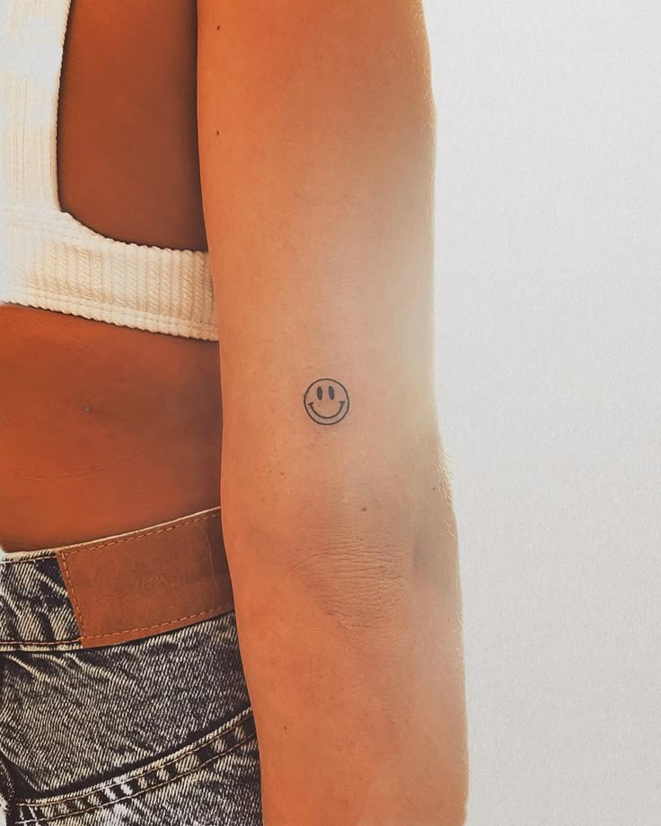 a woman with a smiley face tattoo on her arm