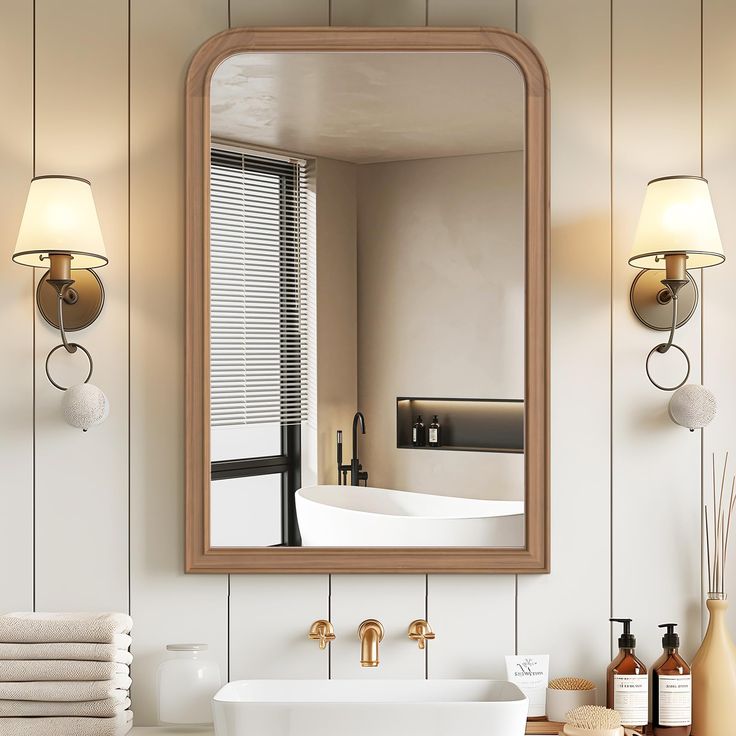 a bathroom sink sitting under a large mirror next to a bathtub and two lamps