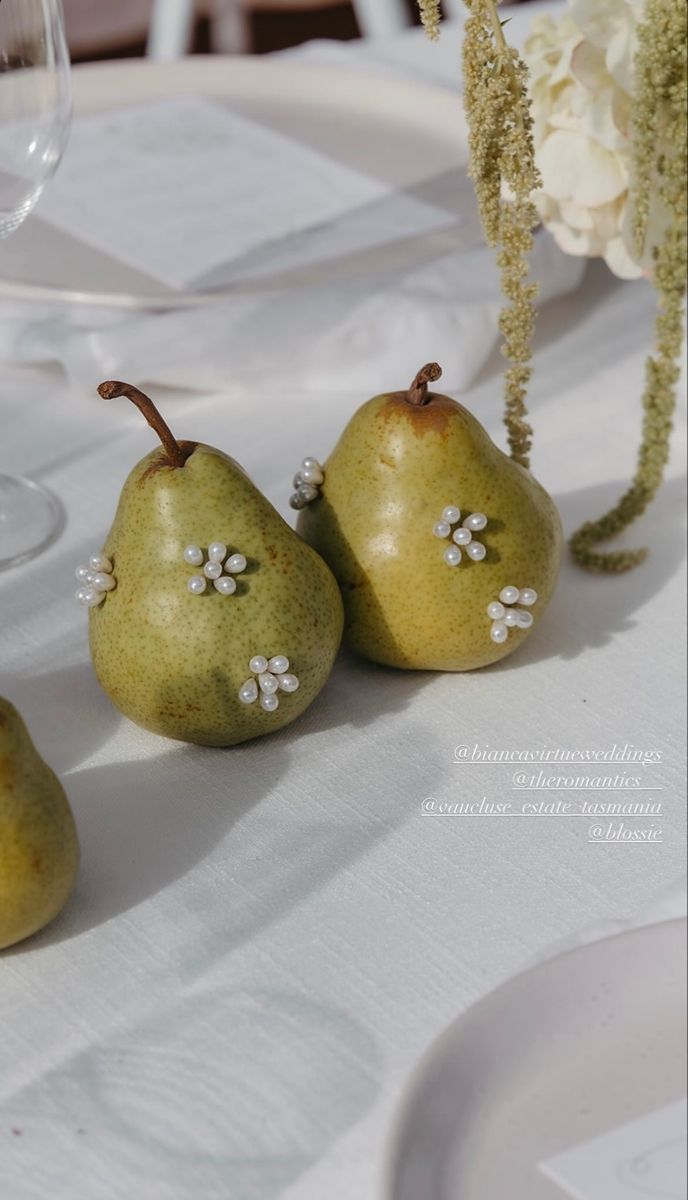 three pears sitting on top of a white table cloth