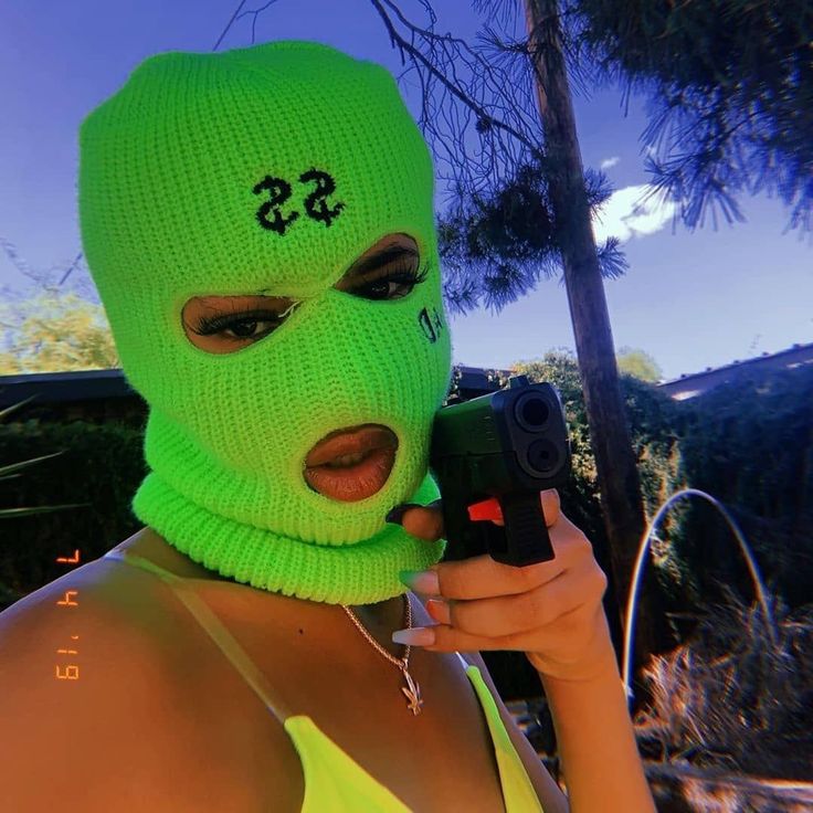 a woman wearing a neon green mask and holding a camera in front of her face