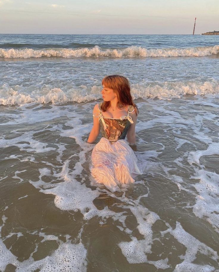 a woman is sitting in the water at the beach