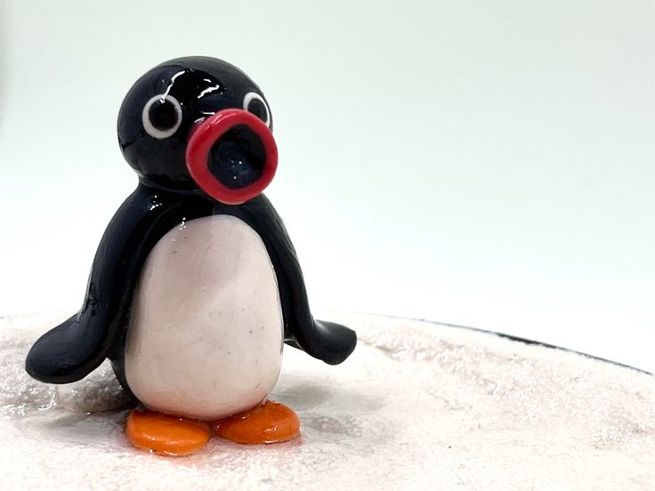 a penguin figurine sitting on top of a white cake covered in icing