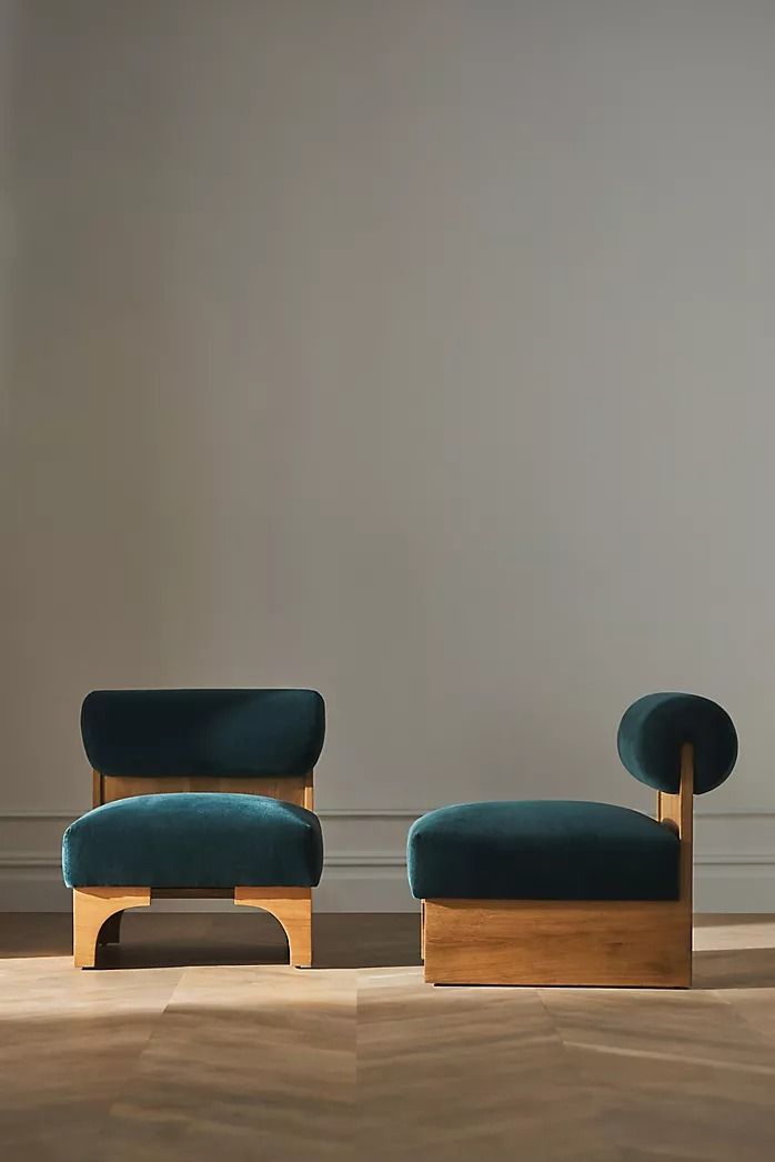 two blue chairs sitting next to each other on top of a hard wood floor in front of a gray wall