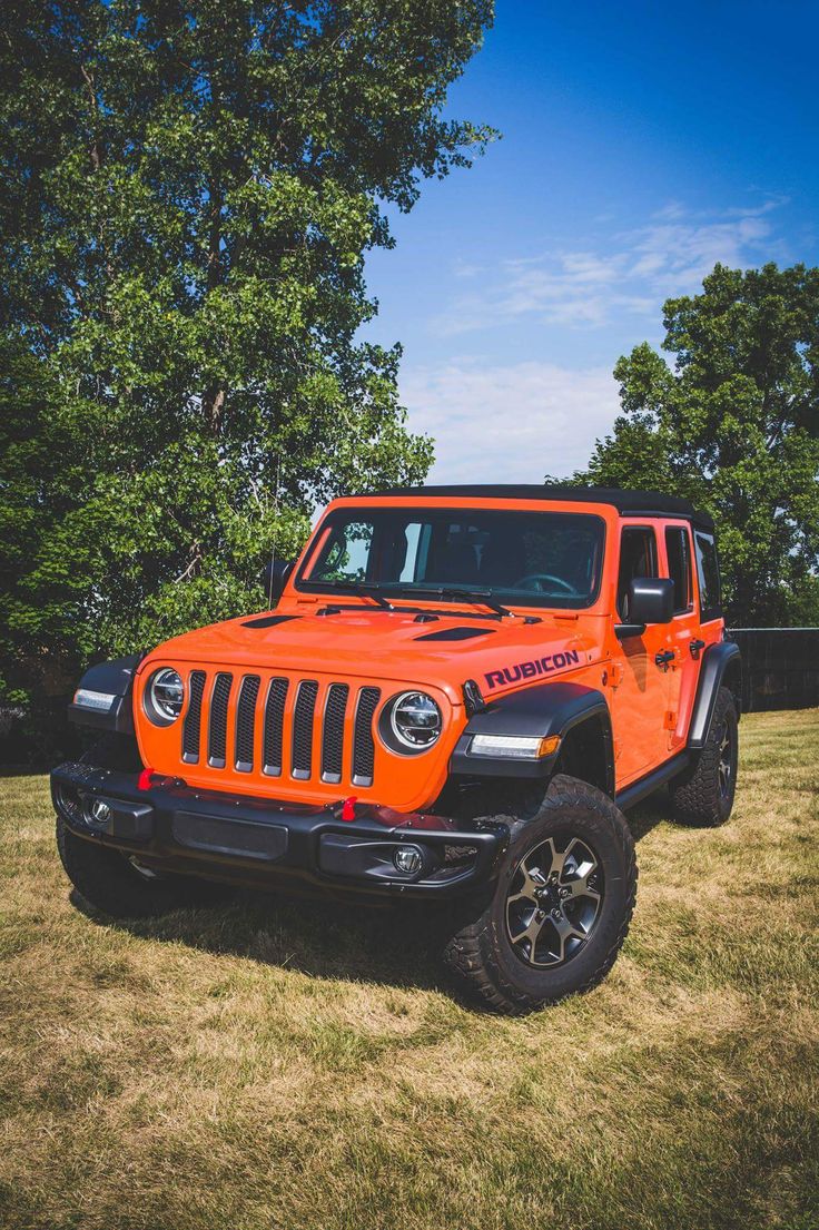 an orange jeep is parked in the grass