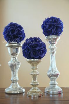 three vases with blue flowers in them on top of a wooden table next to each other