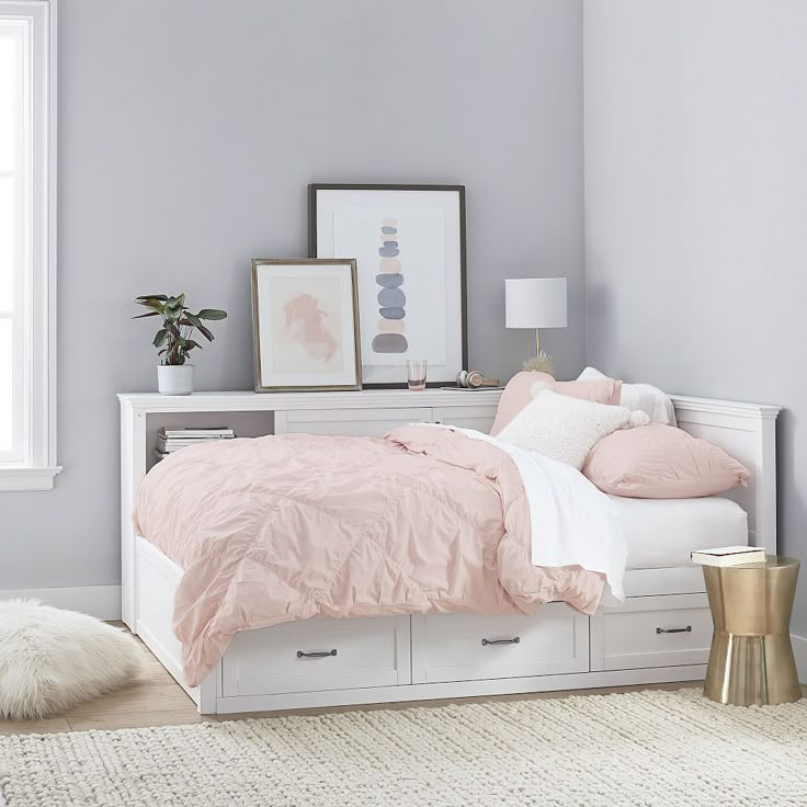 a white bed with pink sheets and pillows