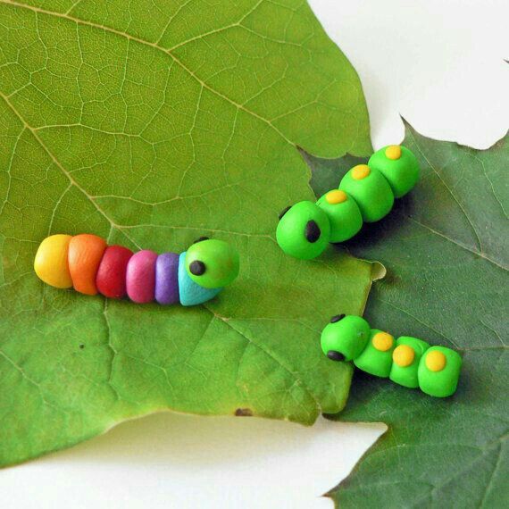 three colorful caterpillars sitting on top of a leaf next to each other