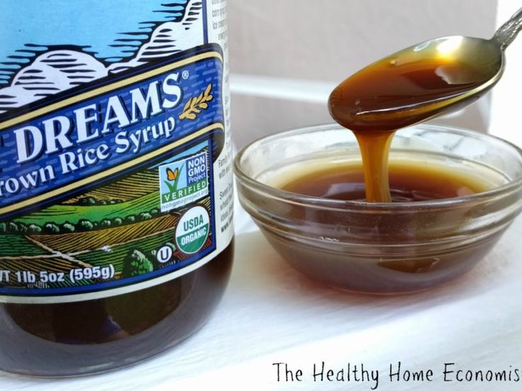 a bottle of brown liquid being poured into a bowl with a spoon next to it