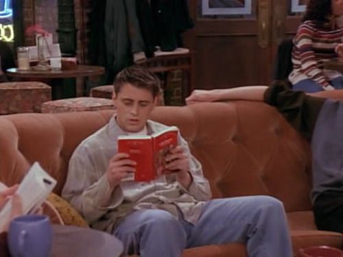 the young man is reading a book on the couch