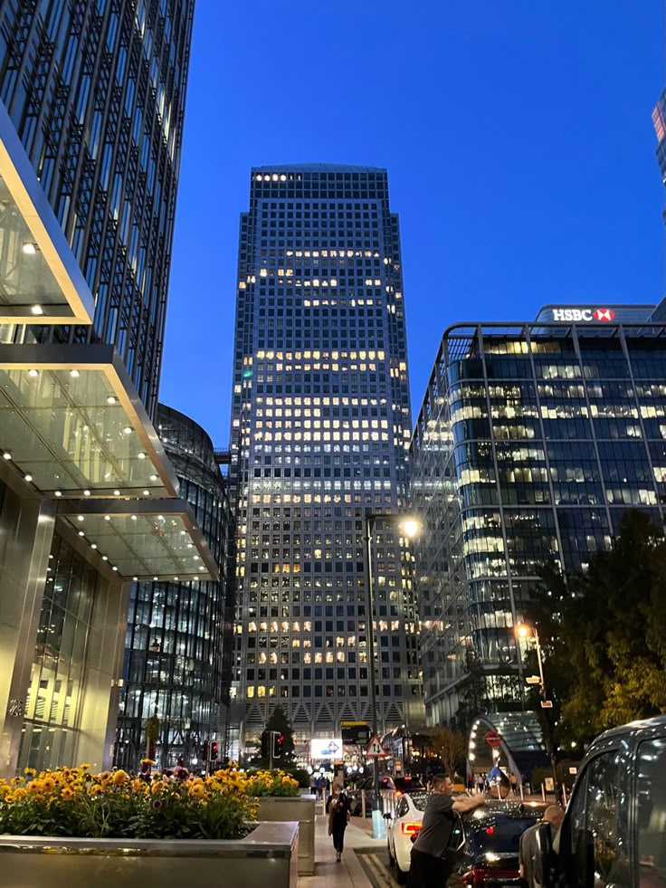 the city is lit up at night with many tall buildings and cars parked on the street